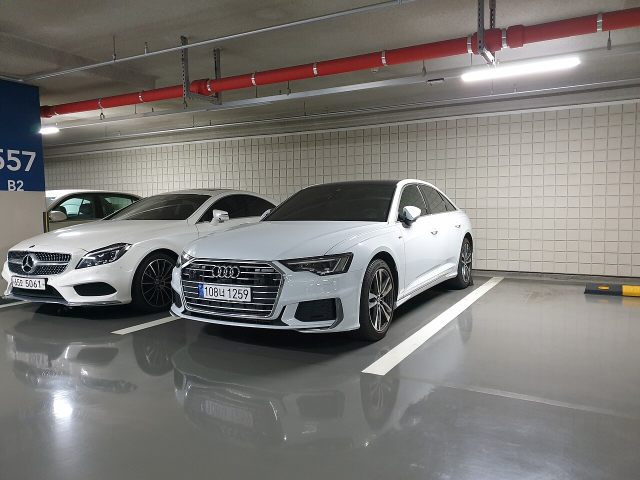 지하주차장에 주차된 흰색 아우디 A6 C8 세단의 앞쪽과 왼쪽 측면