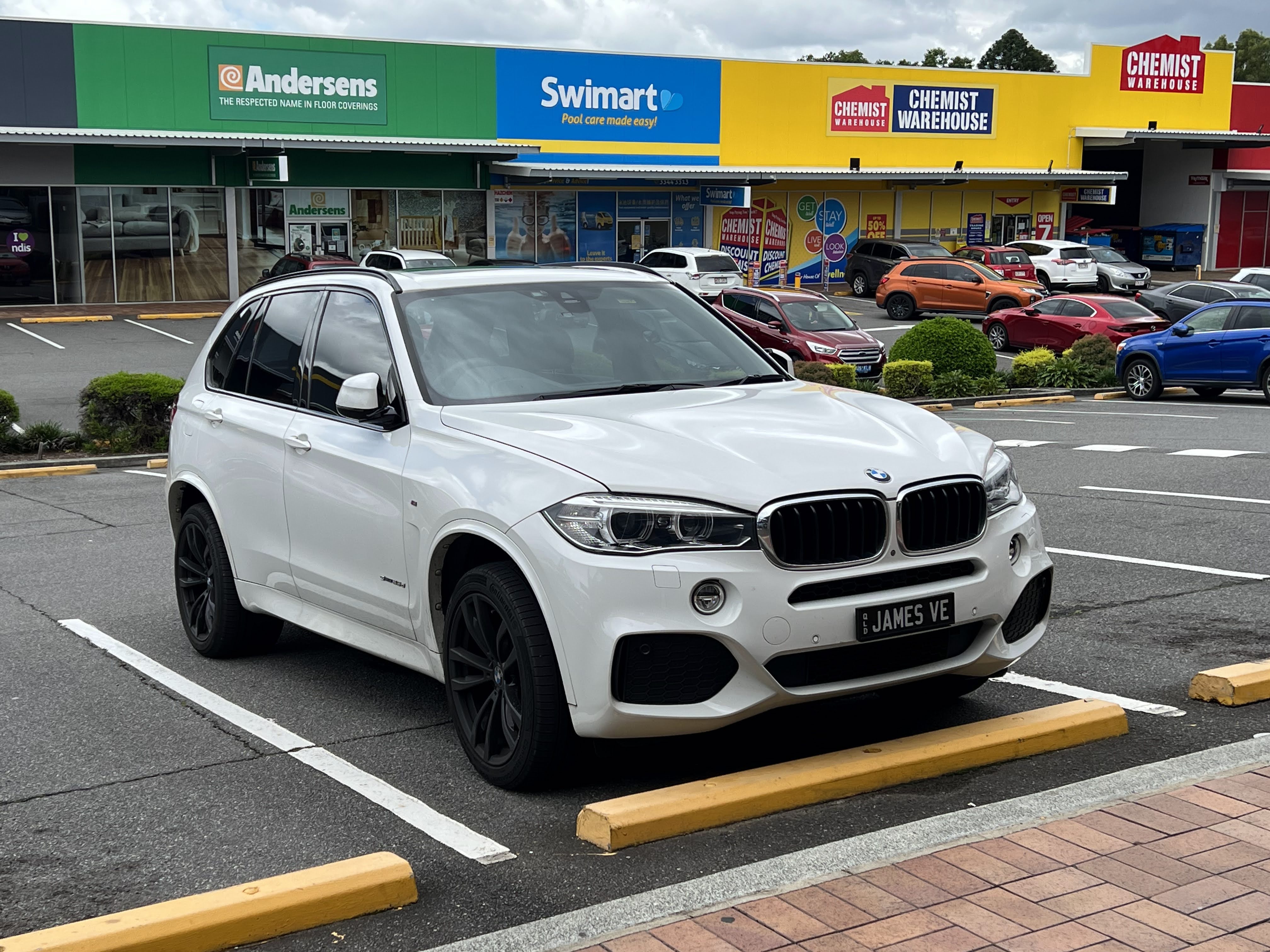 주차된 흰색 BMW X5 F15의 앞쪽과 왼쪽 측면