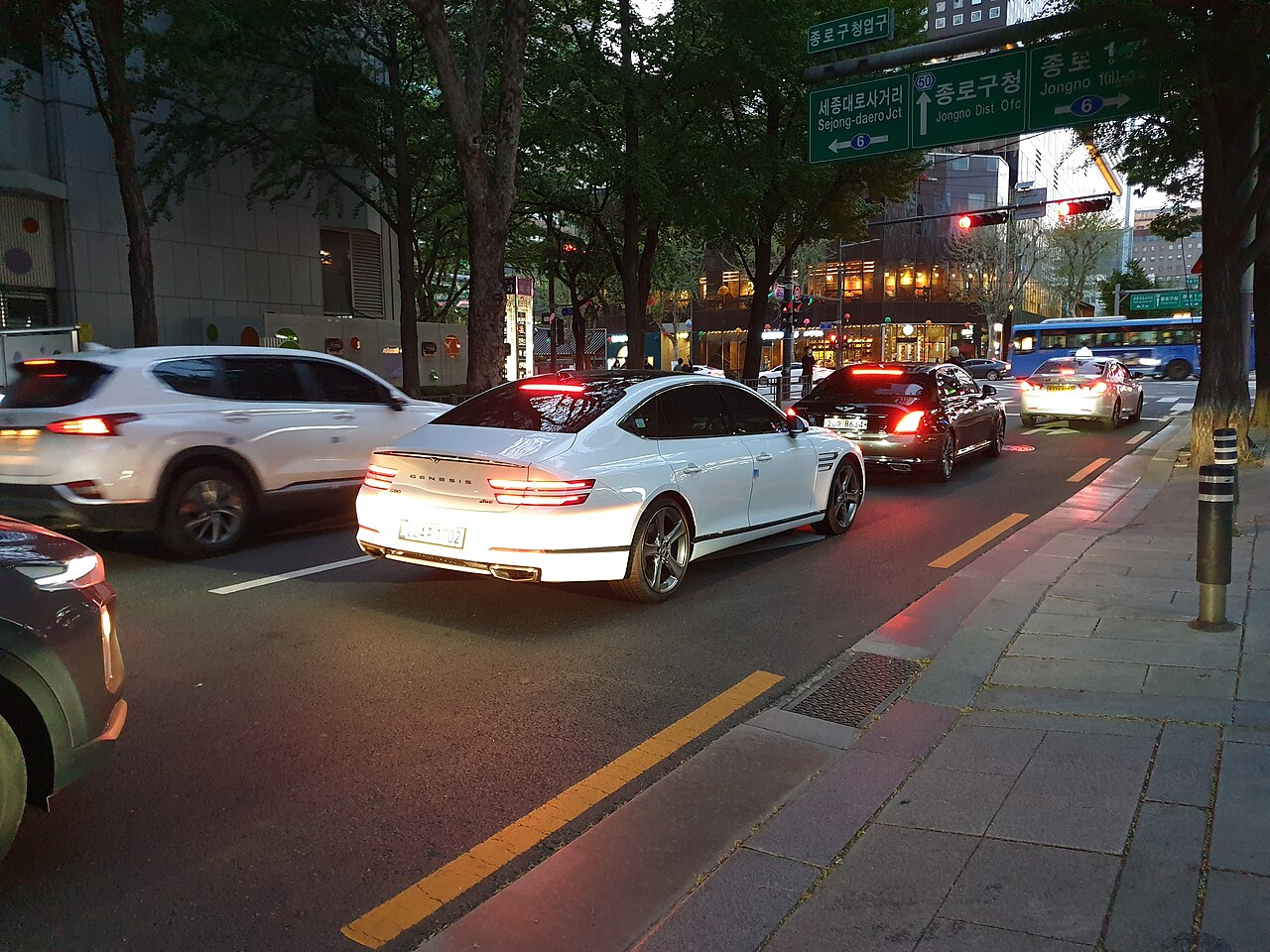 도로 옆에 주차된 흰색 제네시스 G80 RG3의 앞쪽과 왼쪽 측면